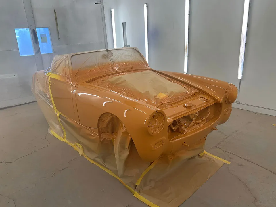 Classic British roadster freshly resprayed orange in the spray booth at OH Works in Fairford