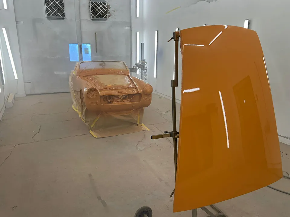 Classic British roadster bodyshell and a freshly painted panel drying in the booth at OH Works in Fairford