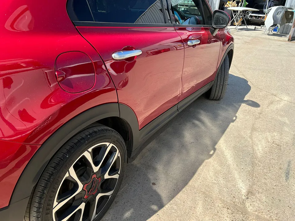 Red Fiat 500X side showing the creased door before repair at OH Works in Fairford