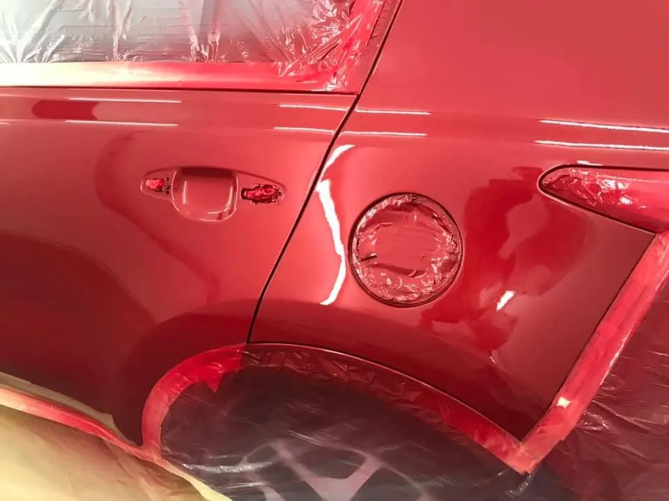 Red Kia Sportage rear quarter masked and primed in the spray booth at OH Works